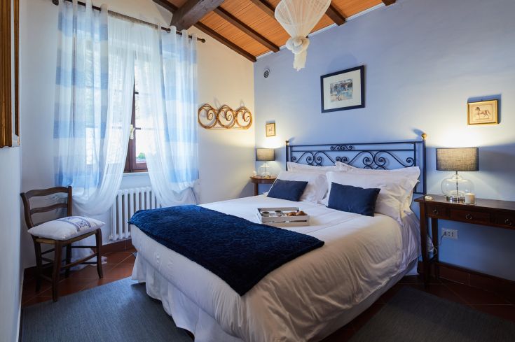 Camera accogliente con letto matrimoniale, decorazioni semplici in stile country e buona illuminazione naturale.