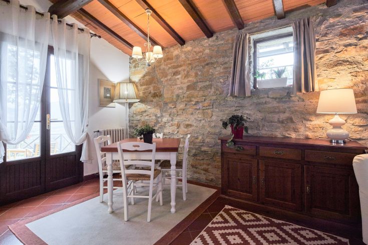 Soggiorno semplice con tavolo da pranzo e elementi in legno, caratterizzato da un'atmosfera calda e rilassante.