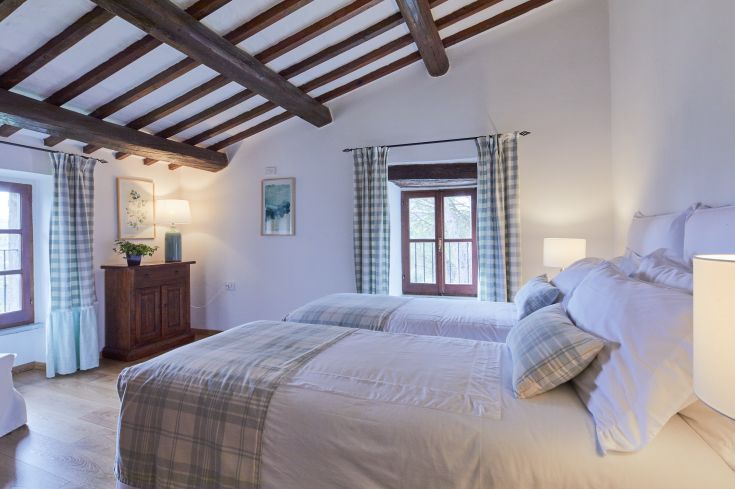 Camera semplice con due letti e luce soffusa. Presenta una finestra che offre uno scorcio sulla natura.