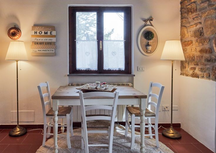 Un'ampia sala da pranzo con un tavolo in legno e lampade semplici. Elementi decorativi discreti sulla superficie.