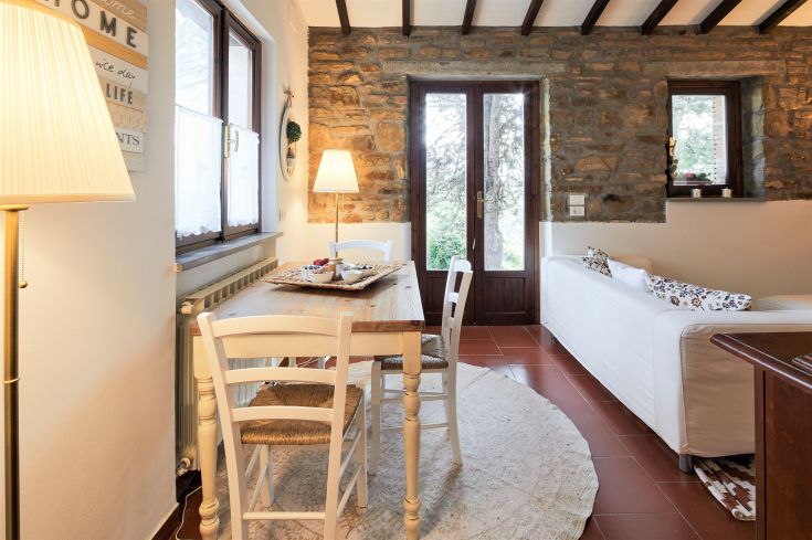 Soggiorno arredato con un tavolo e una lampada, caratterizzato da pareti in pietra che creano un'atmosfera calda.