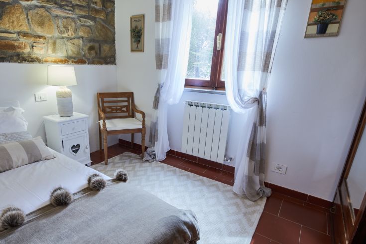 Camera semplice e confortevole con luminosità naturale, grazie a una grande finestra, adatta per il riposo.