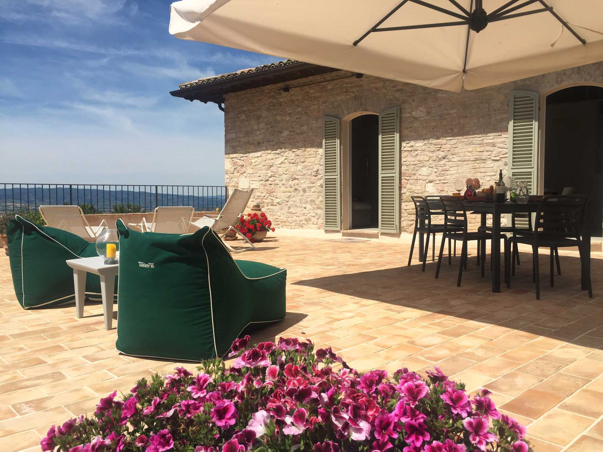 Una spaziosa terrazza attrezzata con mobili semplici e piante fiorite. Un luogo ideale per rilassarsi all'aperto.