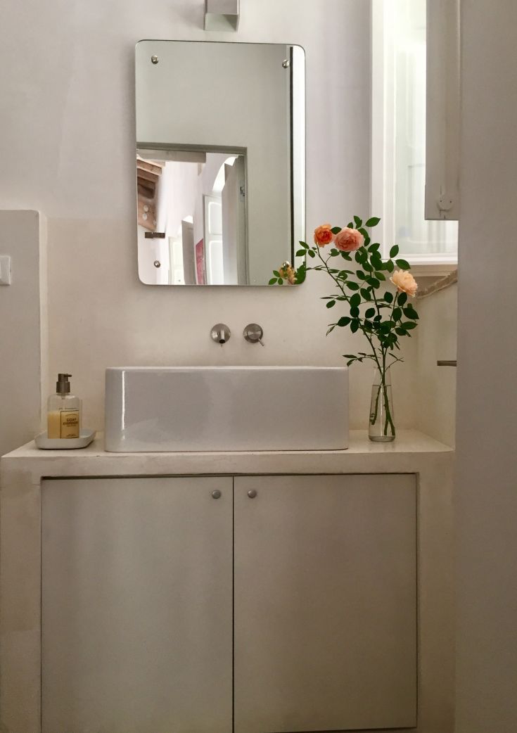 A simple bathroom featuring a modern sink and a vase of colorful flowers for a fresh touch.
