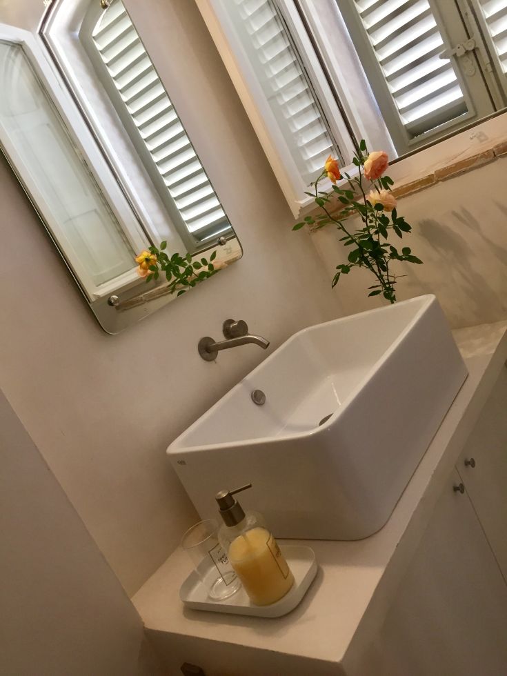 Functional bathroom with simple design, featuring a practical sink and natural light from the window. Green plants present.