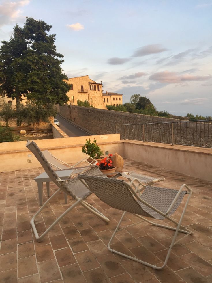 Terrace with chairs overlooking historic buildings. A peaceful spot for relaxation.