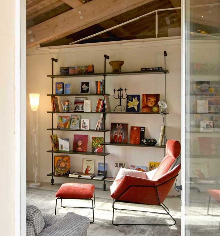 A simple reading space featuring a rich bookshelf, comfortable chairs, and natural lighting.