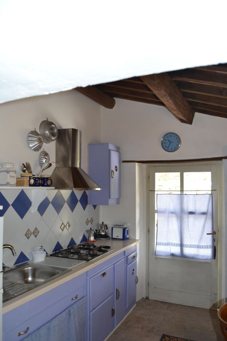 A cozy, simple kitchen featuring wooden furniture and touches of blue, perfect for socializing.