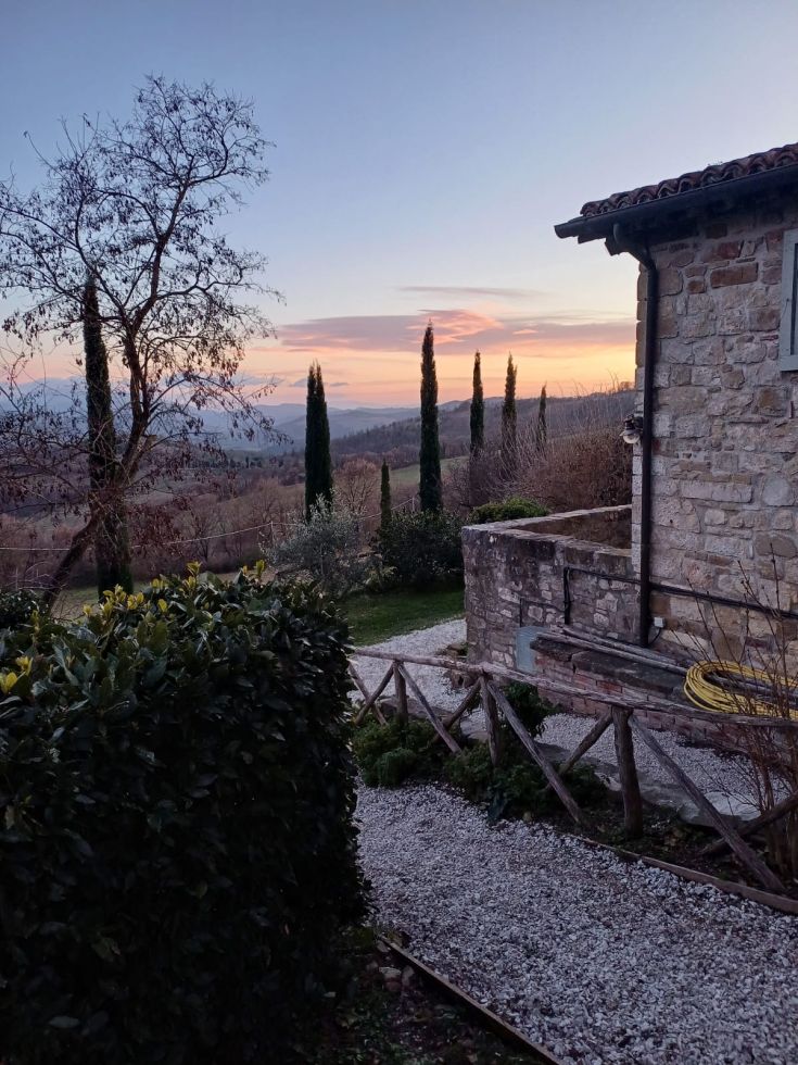 A stone farmhouse located in the peaceful Umbrian countryside, surrounded by gentle hills.
