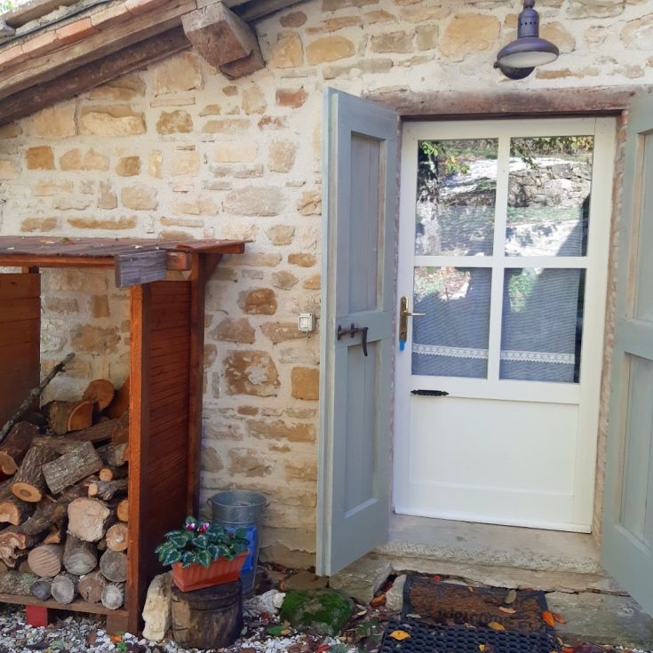 A welcoming door opens to the natural landscape of Umbria, framed by a typical stone farmhouse.
