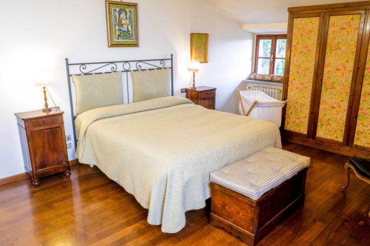 Simple bedroom featuring a double bed, wooden wardrobe, and soft lighting.