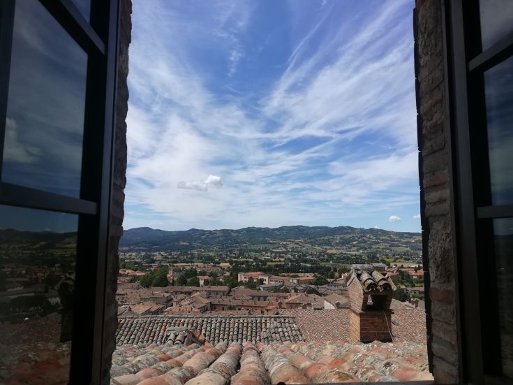 View from a window showcasing surrounding rooftops and hills in the background.