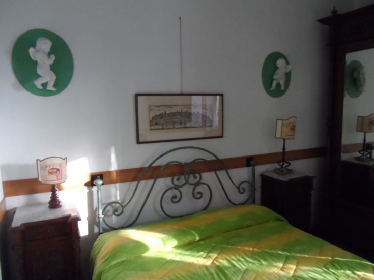 Camera matrimoniale con luce naturale, arredamento classico e dettagli artigianali, ambiente accogliente per il soggiorno.