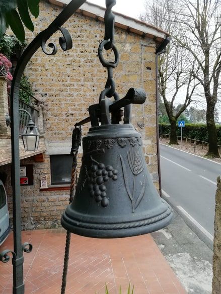 Campana in ferro battuto dal design semplice, appesa in una zona rurale tranquilla.