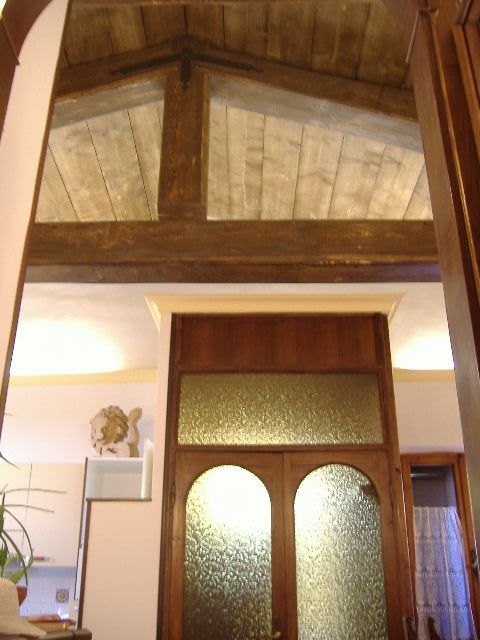 Interno di una casa con soffitto in legno a travi e porte in vetro decorato.