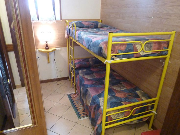 Camera con letti a castello, lampada da tavolo e arredamento sobrio e accogliente.