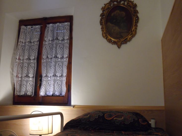 Camera accogliente con un letto semplice e alcune decorazioni classiche. Spazio luminoso e tranquillo.