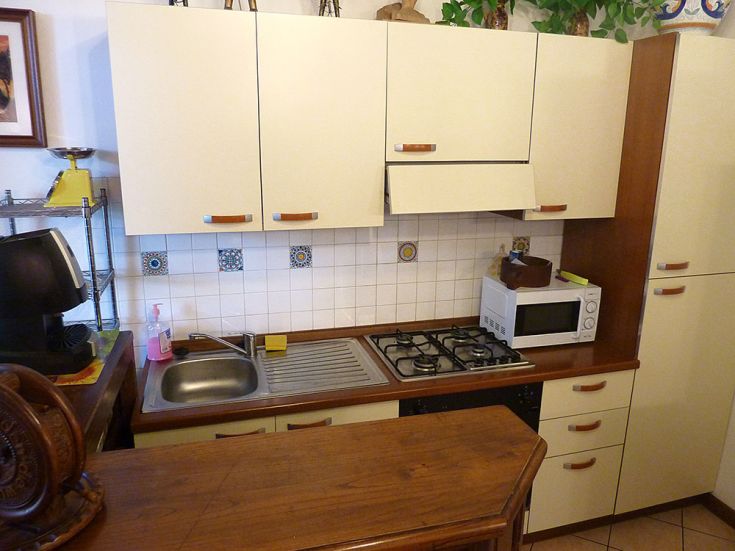 Cucina semplice con mobili in legno e finiture artigianali, dotata di attrezzature moderne per un uso quotidiano.