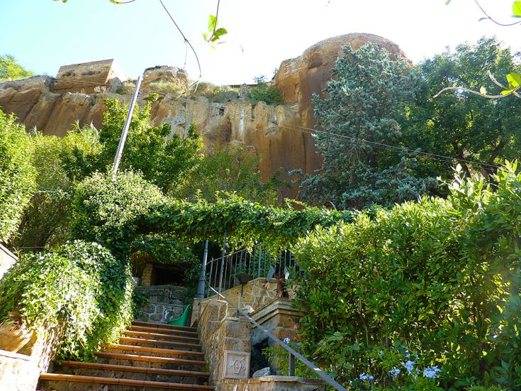 Una scalinata immersa nel verde che conduce a un ampio edificio in pietra.