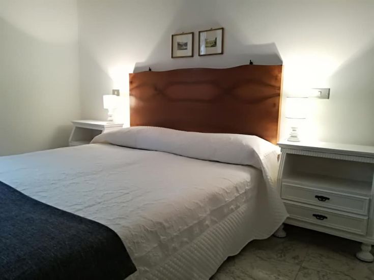 Spazio intimo con letto matrimoniale, illuminato da lampade, con un design sobrio e funzionale.