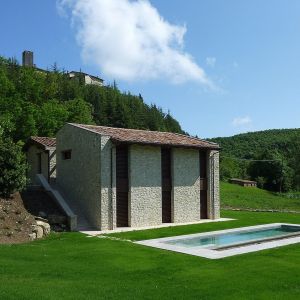 A building in a green area, featuring a pool, which used to be a mill, perfect for relaxation.