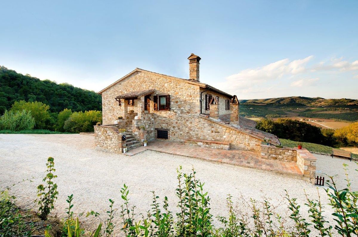 Un elegante casale in pietra circondato da un'area verde, perfetto per momenti di relax.