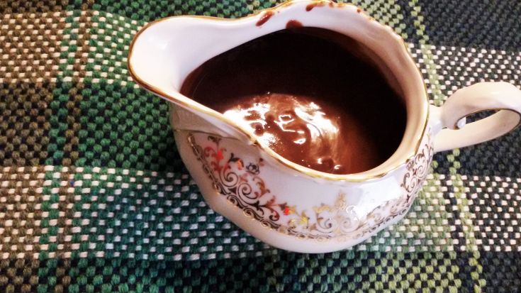 Eine Keramiksauce mit einem Schokoladendesign auf einem karierten Tischdecken.