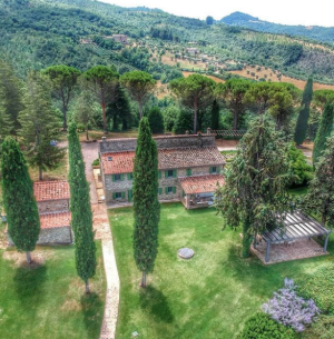 Panorama di una villa immersa nel verde, circondata da alberi e un paesaggio naturale.