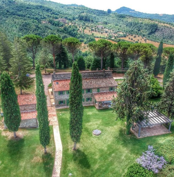 Panorama di una villa immersa nel verde, circondata da alberi e un paesaggio naturale.