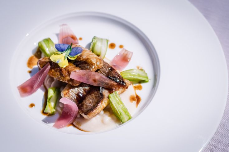 Un piatto con pesce e verdure fresche, decorato con elementi floreali, perfetto per una cena raffinata.