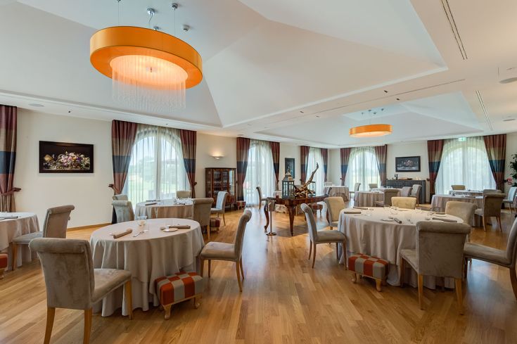 Locale ristorante arredato in modo semplice, con tavoli sistemati per i clienti e buona illuminazione naturale.