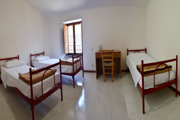 Functional room with single beds and simple decor, ideal for hostel guests.