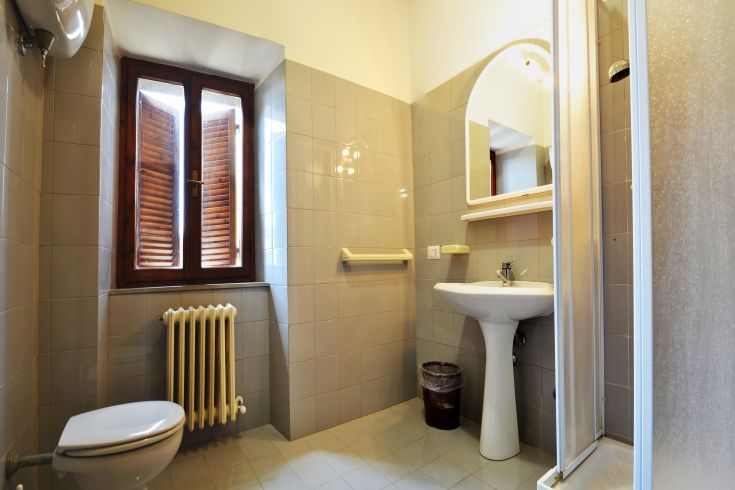 Bright and modern bathroom in a historic building, featuring a window and convenient sanitary facilities.