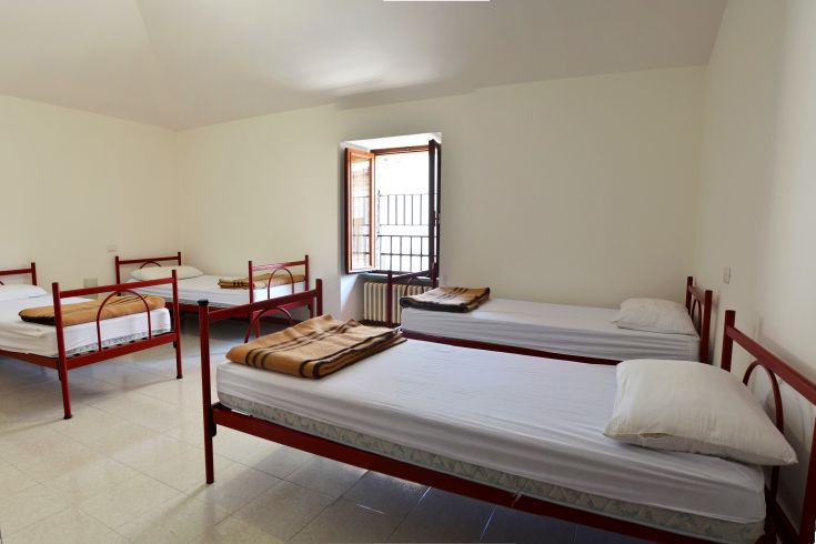 A hostel room with single beds, suitable for groups, featuring good lighting and a comfortable environment.