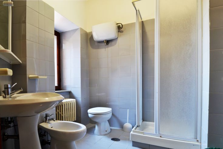 Modern bathroom featuring a shower and sanitary ware, located in a bright space with gray tiles.