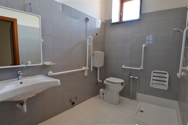 A simple, well-organized bathroom featuring a shower and mirror in a bright and tidy space.
