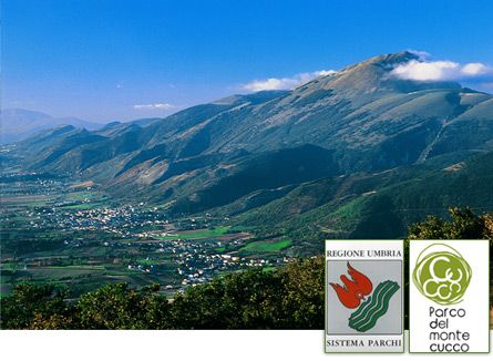 Scene of Monte Cucco Park in Umbria, featuring green hills under a clear sky.