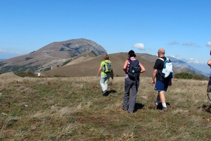 Group of hikers in the mountains, surrounded by a natural scene with a clear sky.