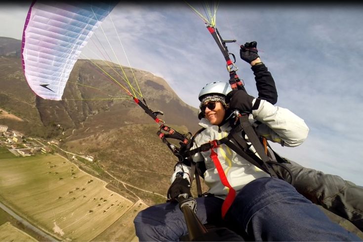 A paragliding activity in the Umbrian hills. Light clouds and lush green landscape can be seen in the distance.