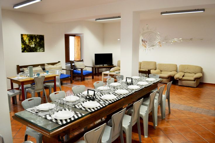 Spacious common room in the hostel, featuring a set dining table and a cozy relaxation area.