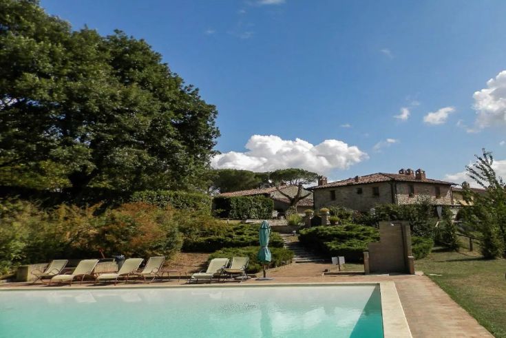 Casale in pietra con piscina nel paesaggio verde dell'Umbria.