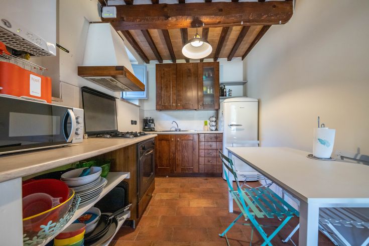 Cucina di un edificio rustico, con mobili in legno e apparecchi moderni, caratterizzata da un'atmosfera semplice e accogliente.