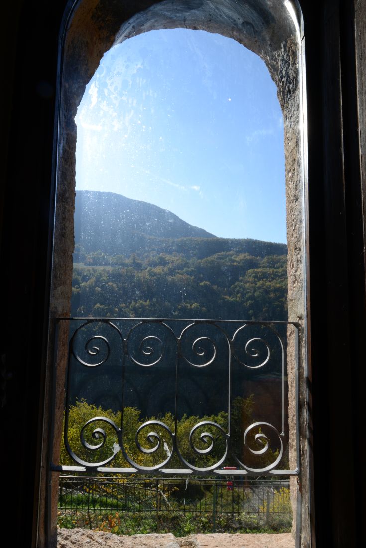 Mountain panorama view with nature seen through a window, featuring intricate iron details.