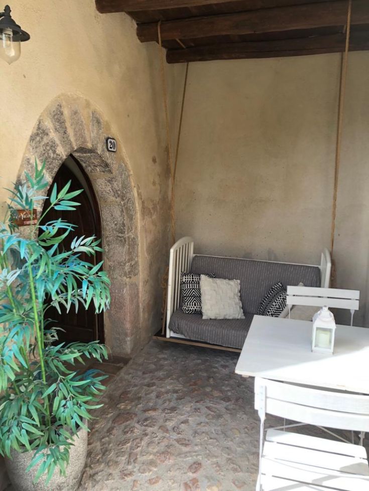 A cozy space with a sofa and a table, surrounded by rustic elements and green plants.