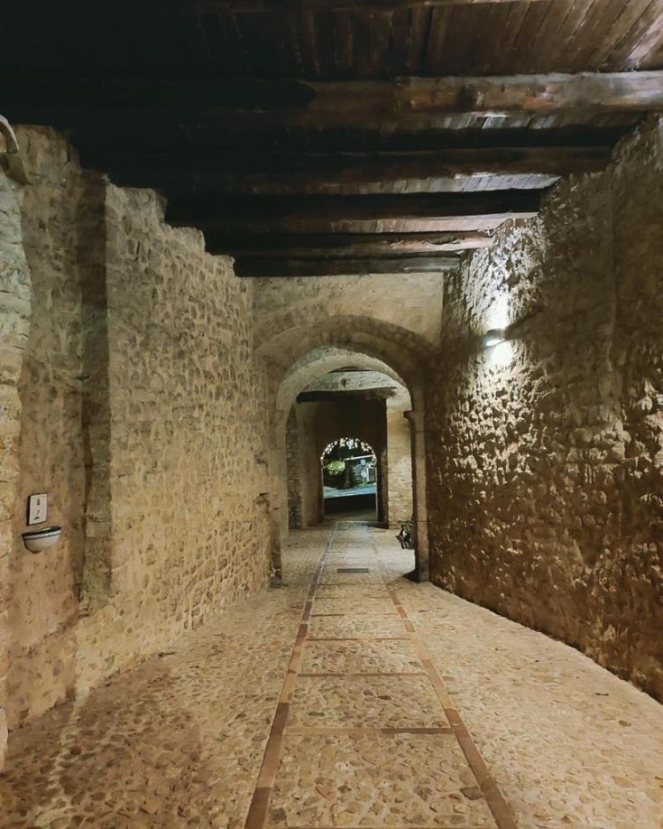 A stone corridor featuring walls made of stone and wooden ceilings, evoking historical architectural styles.