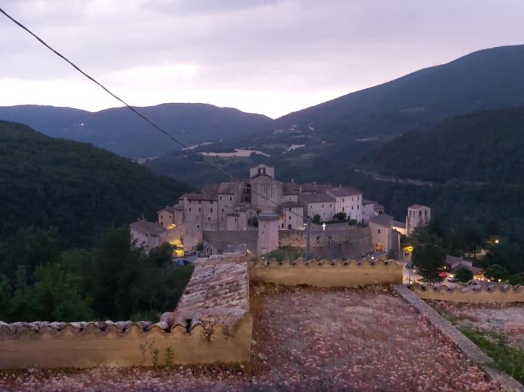 A peaceful scene of an ancient village surrounded by green hills and a cloudy sky, evoking a serene atmosphere.
