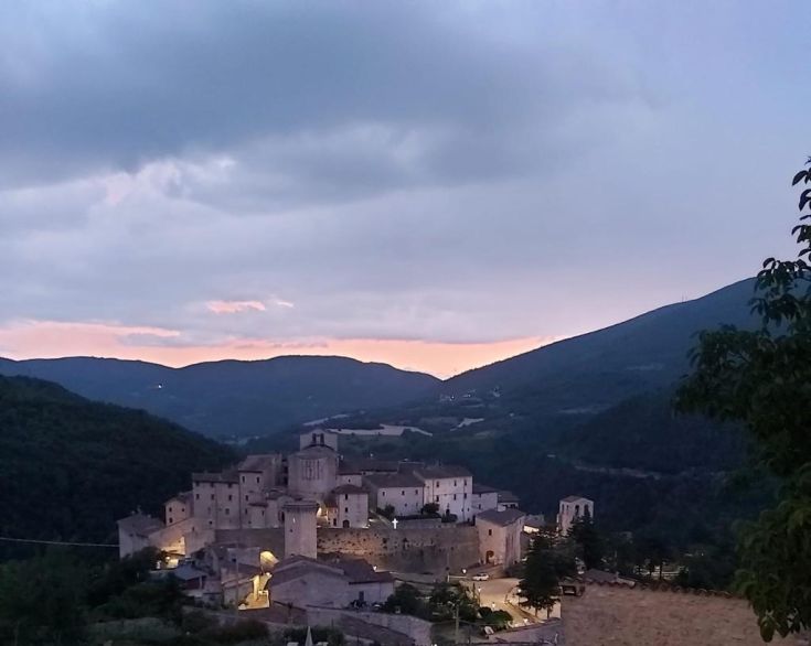 A peaceful village surrounded by mountains, enhanced by the warm light of sunset.