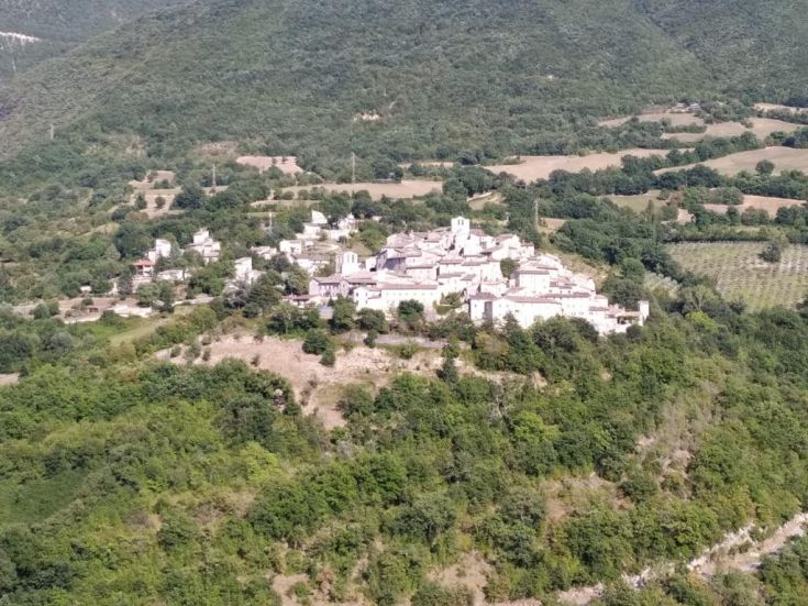 A historic village surrounded by hills, featuring cobblestone streets and traditional houses in a peaceful setting.