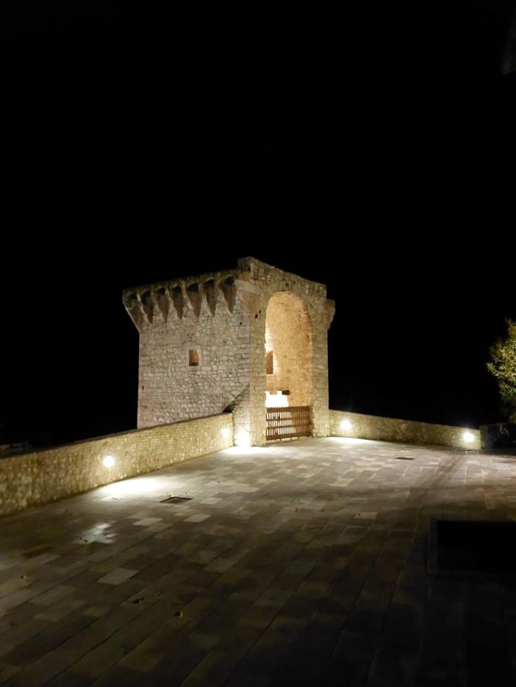 Ancient stone tower illuminated in the calm night, surrounded by a peaceful environment.