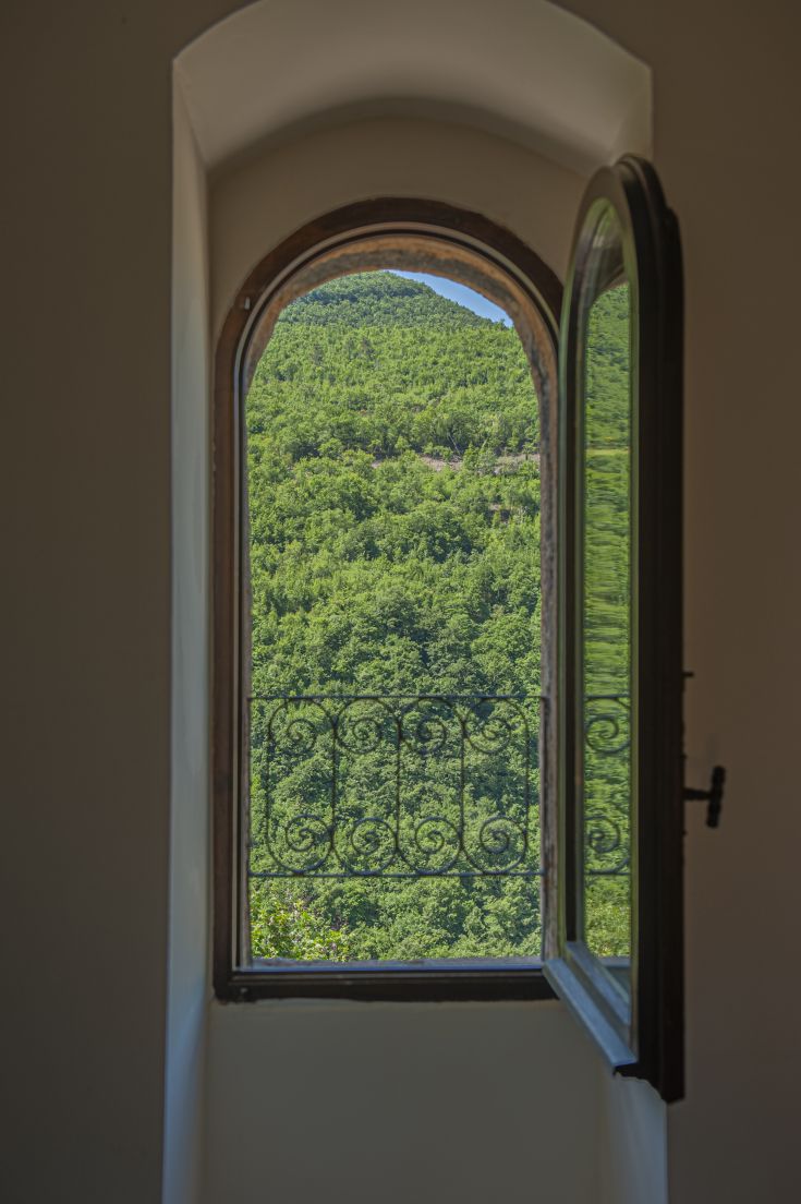 A green hilly landscape viewed through an open window.